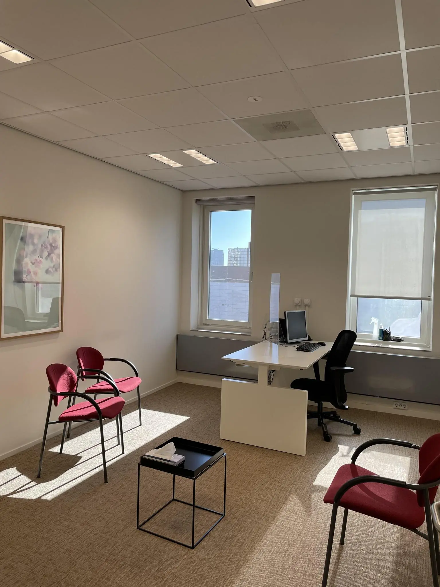 Licht en modern kantoor aan de Johan Cruijff Boulevard met bureau, rode stoelen en groot raam.